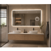 Moderní koupelna s velkým LED zrcadlem BESTECO Magnify 120x65 cm se zapnutým teplým podsvícením, umístěným nad dřevěnou skříňkou se dvěma umyvadly. V pravé části zrcadla je viditelný integrovaný zvětšovací kruh.