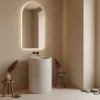 Bílé umyvadlo z litého mramoru Merlo umístěné pod moderním klenutým LED zrcadlem